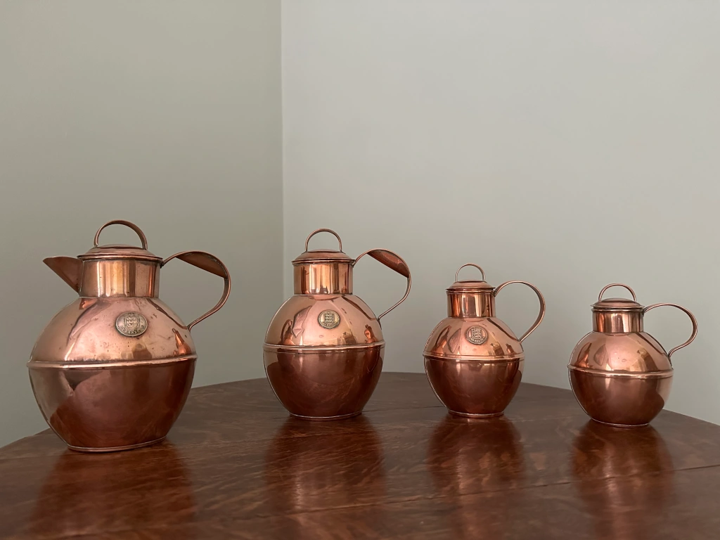 Four antique copper Guernsey milk cans that have been polished to a nice shiny rose finish