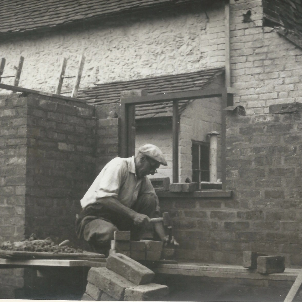 Black and white photo of an elderly bricklayer at work